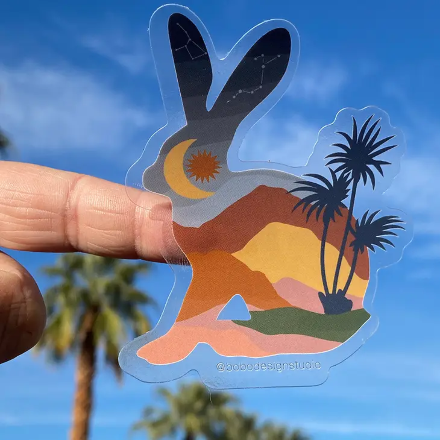 Hand holding bunny sticker up to the sky to show the clear outline