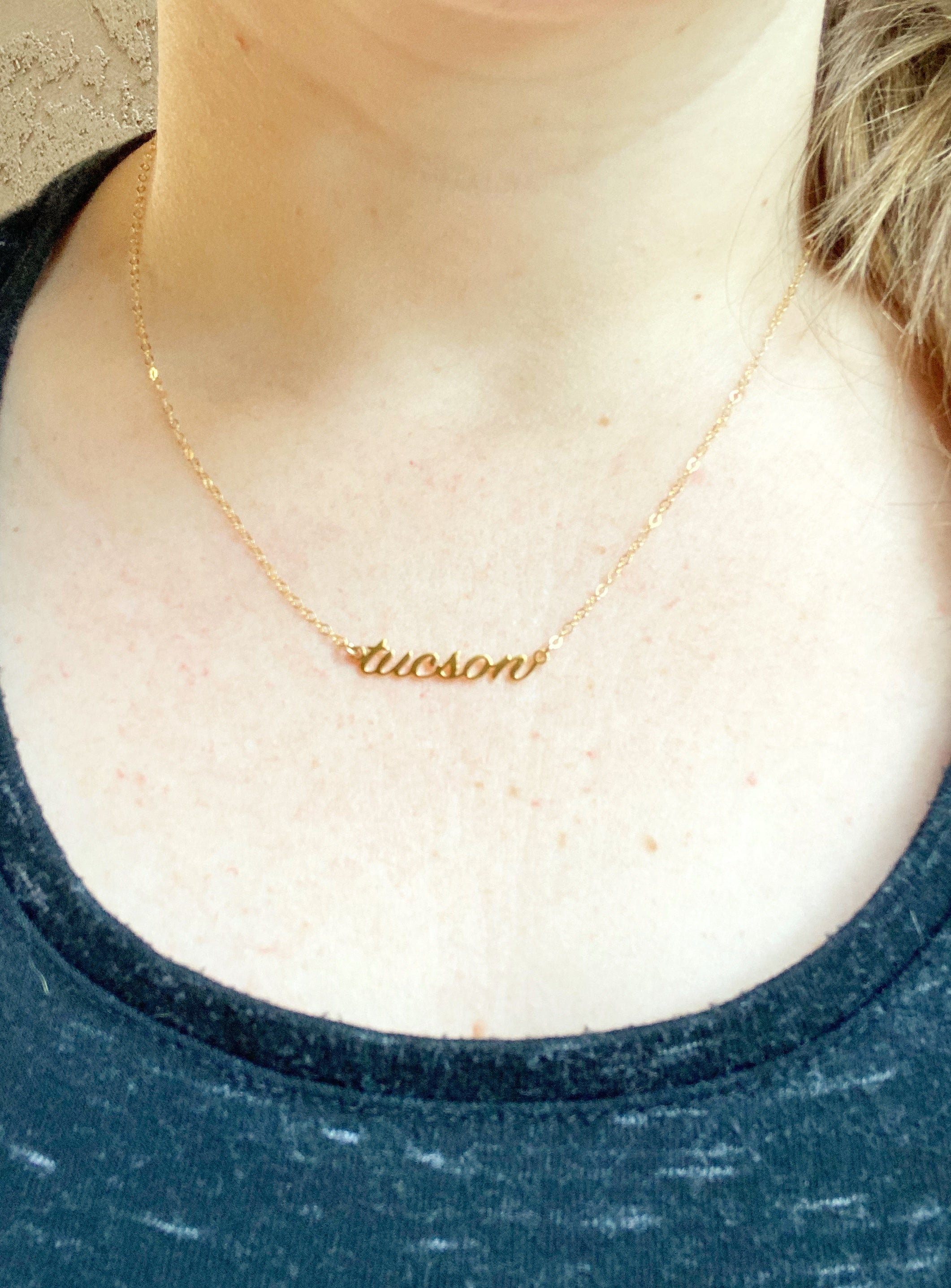 Woman wearing gold script tucson necklace