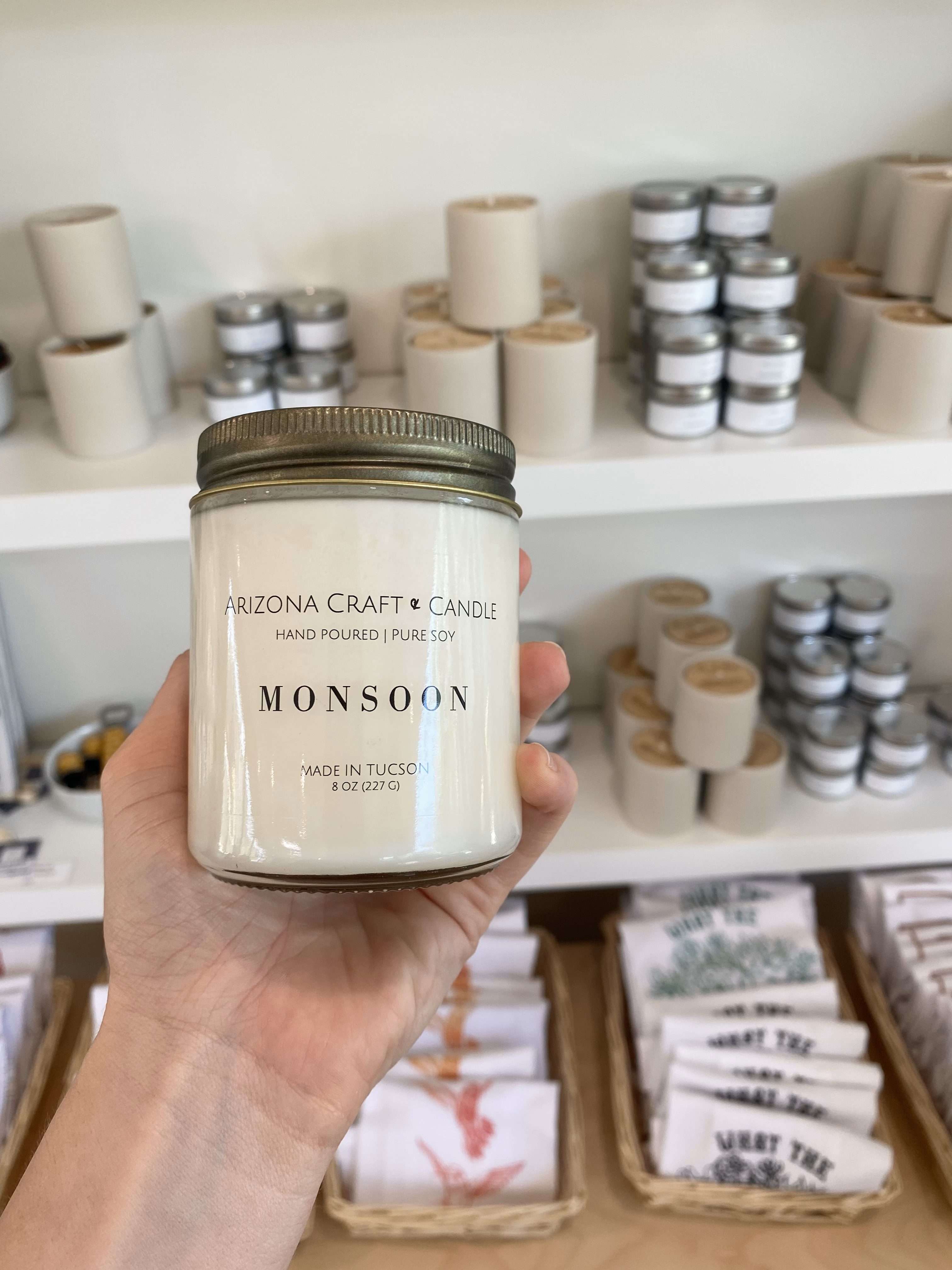 Monsoon candle being held in front of a shelf of other candles