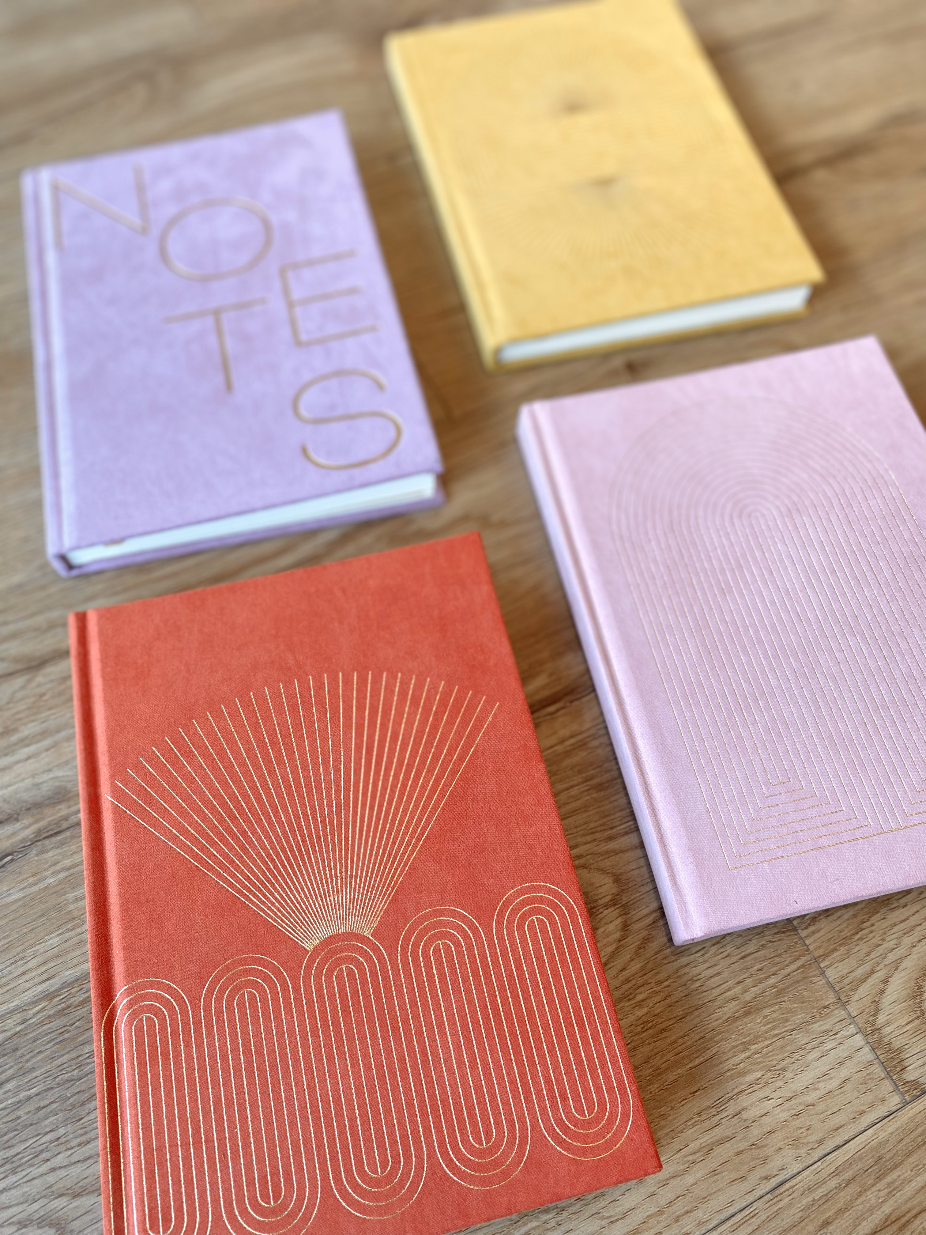 Flatlay of red, purple, yellow, and pink journals