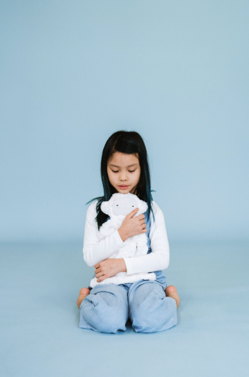 Elementary aged child kneeling on the ground holding yeti slumberkin