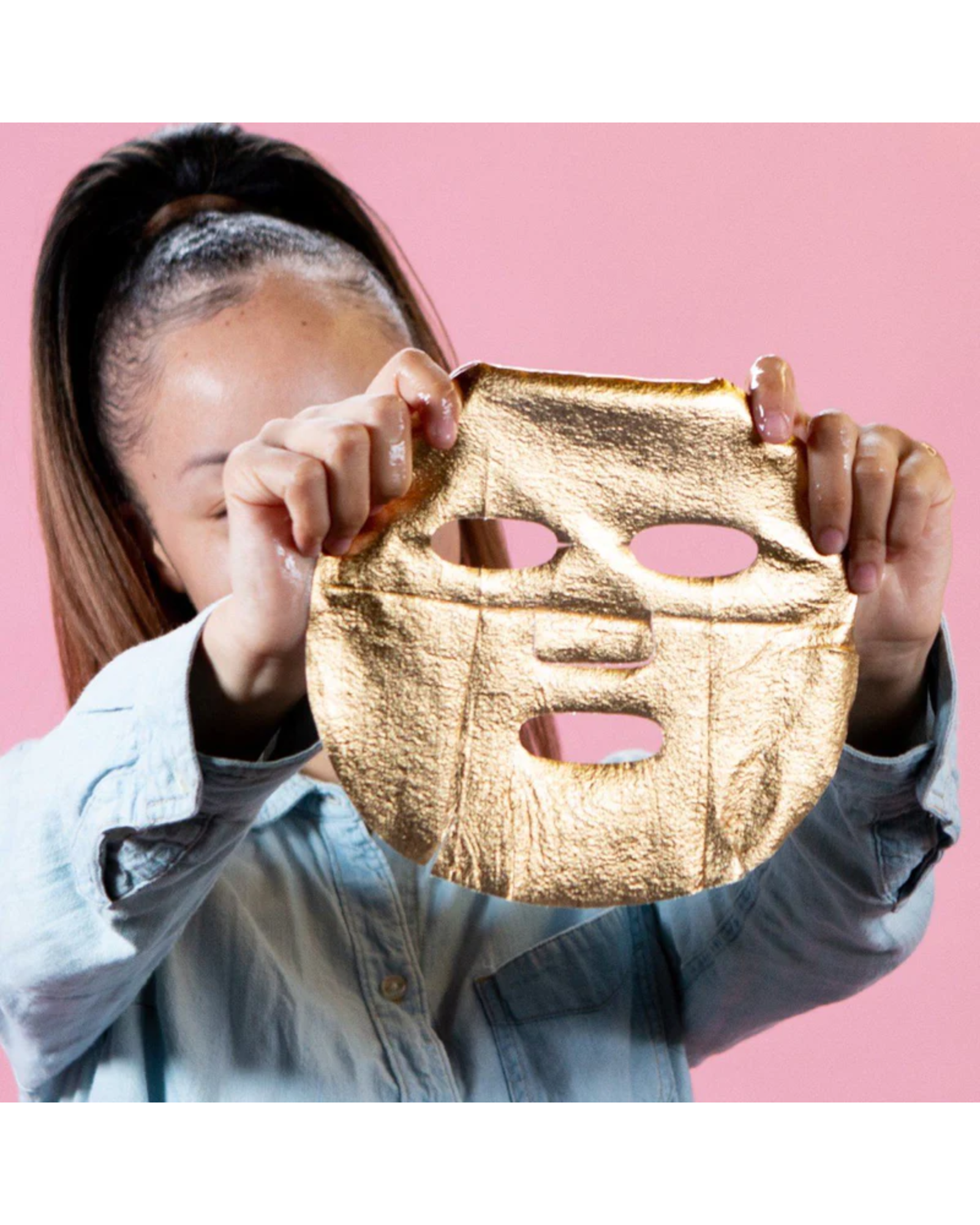 Gold face mask held in front of a person