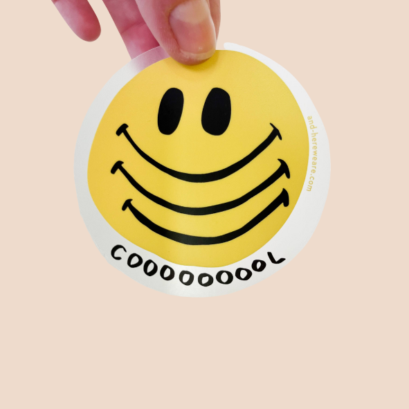Hand holding up smiley face sticker to show clear backing