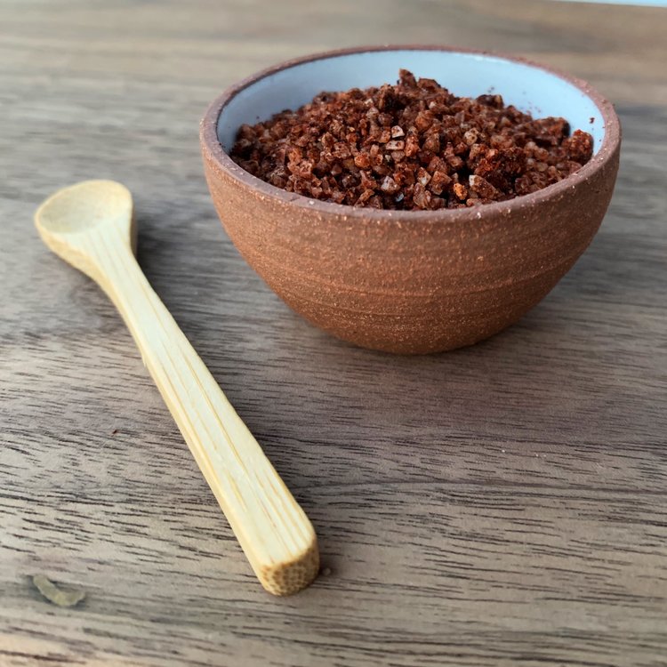 Ceramic bowl of hatch red chile salt next to a wooden spoon