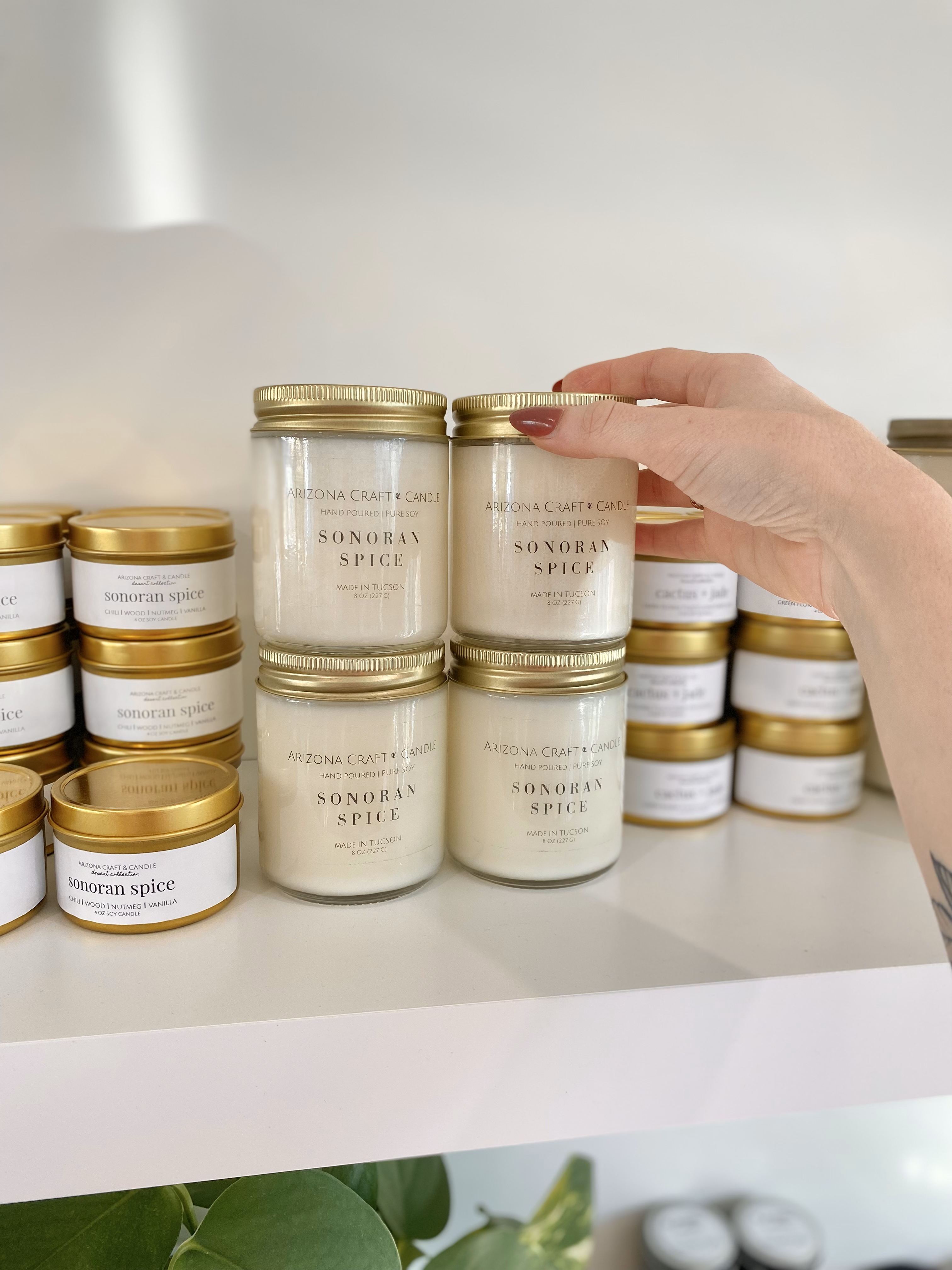 Person reaching for a sonoran spice candle on a shelf